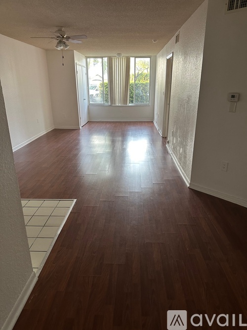 A long hallway with wood floors and a ceiling fan.