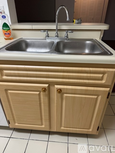A kitchen sink with a wooden cabinet below it.