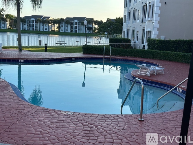A pool with a red tile walkway and a metal ladder.