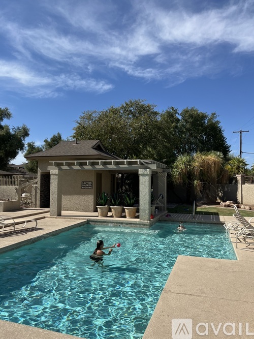 A person is swimming in a pool with a house and trees in the background.