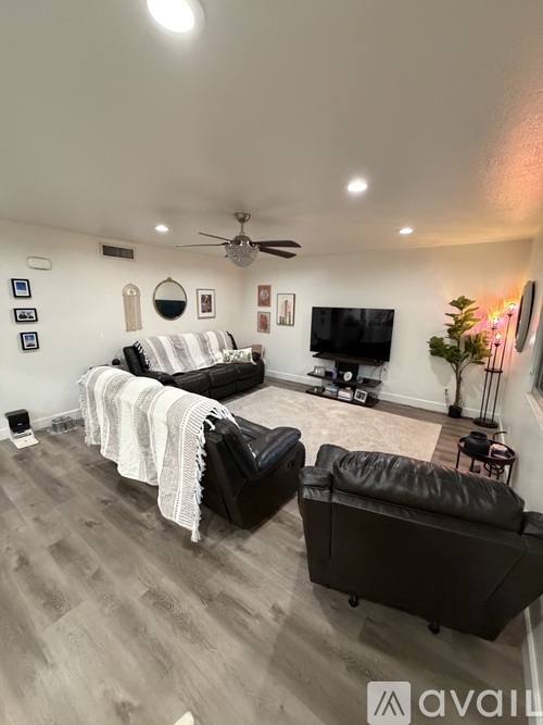 A living room with a black leather couch and a white blanket on it.