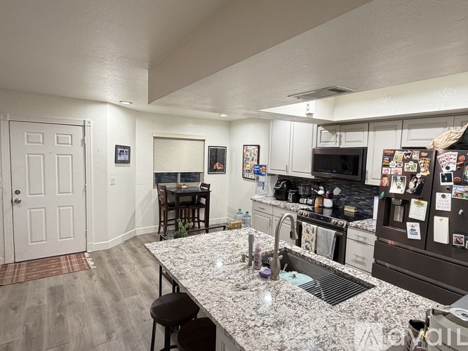 A kitchen with granite countertops and a refrigerator covered in magnets.
