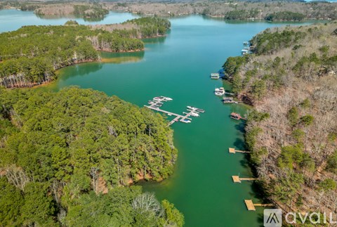 An aerial view of a lake surrounded by trees with boats docked at the pier.