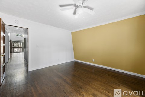 A room with a ceiling fan and wooden flooring.