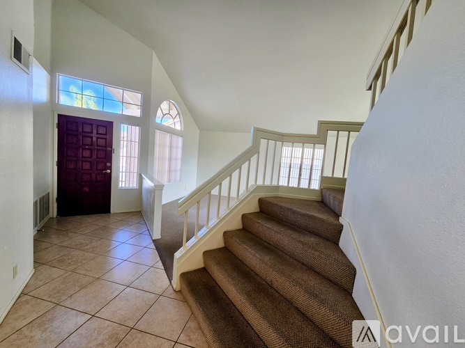 A staircase with a brown carpeted runner and white balusters leads up to a second floor.
