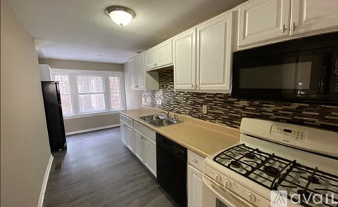 A kitchen with white cabinets and a white stove top oven.
