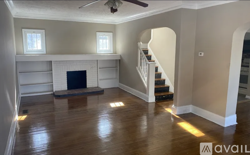 A spacious living room with a fireplace and stairs leading to the upper floor.
