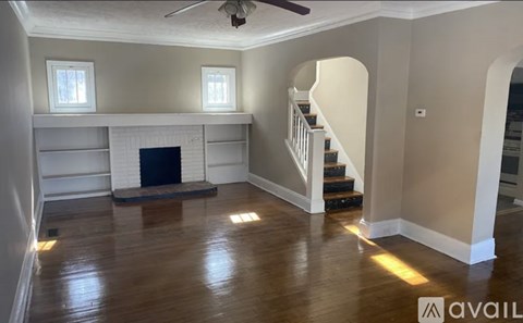 A spacious living room with a fireplace and stairs leading to the upper floor.