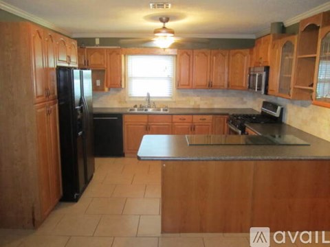 A kitchen with wooden cabinets and a black refrigerator.