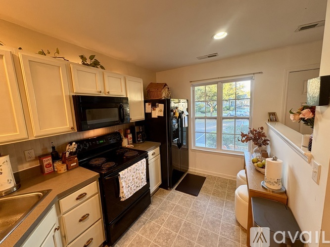 A kitchen with black appliances and white cabinets.