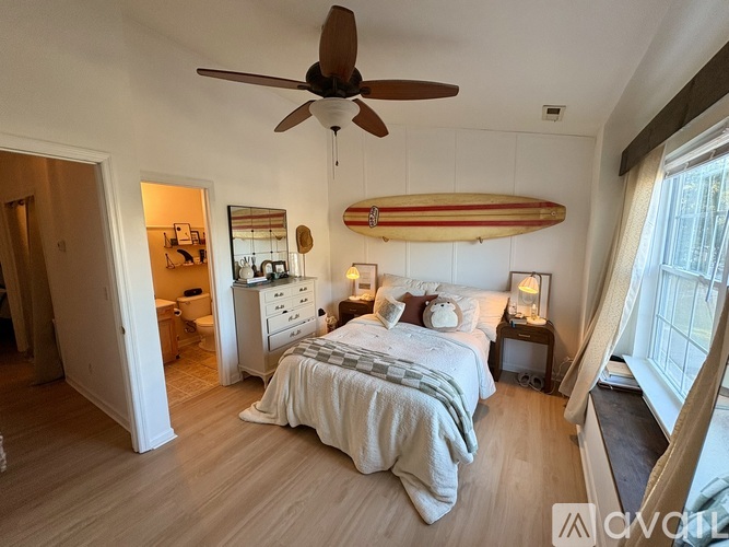 A bedroom with a surfboard hanging from the ceiling.
