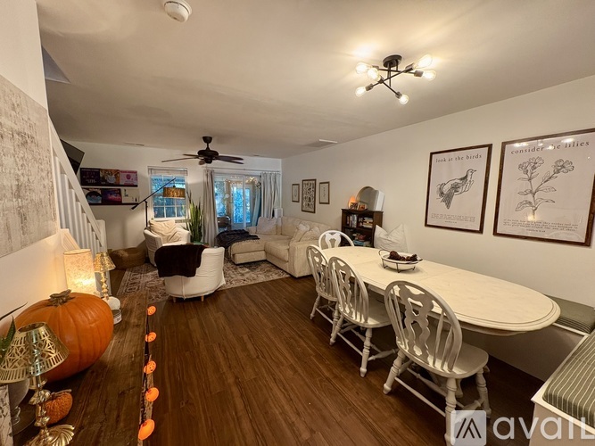 A living room with a dining table and chairs, a pumpkin on the floor, and a ceiling fan.