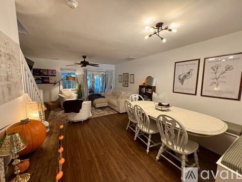 A living room with a dining table and chairs, a pumpkin on the floor, and a ceiling fan.