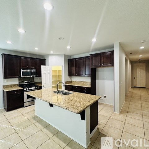 A kitchen with granite countertops and dark brown cabinets.