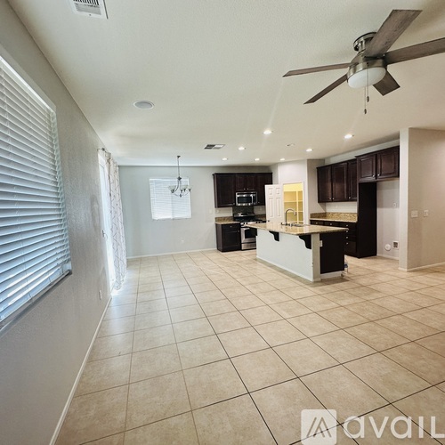 A spacious kitchen and living room with a ceiling fan and tiled flooring.
