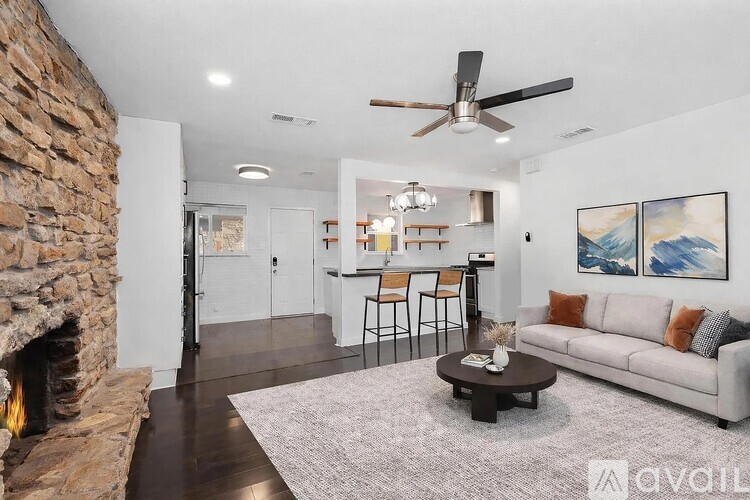 A living room with a stone fireplace and a grey couch.