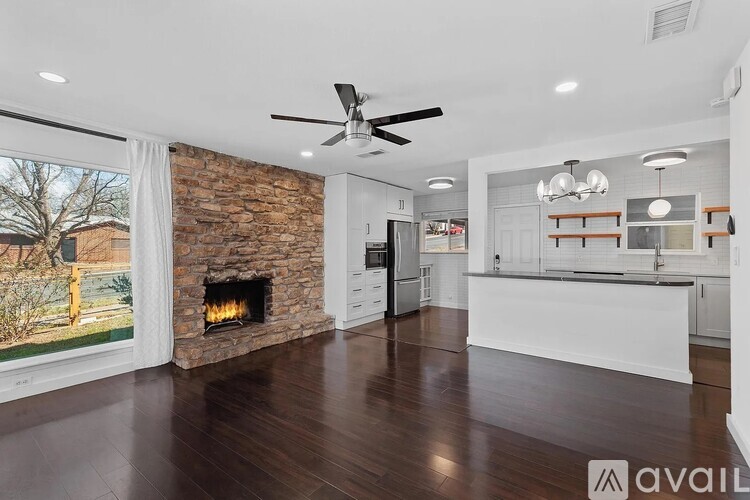 A modern kitchen with a stone fireplace and wooden floors.