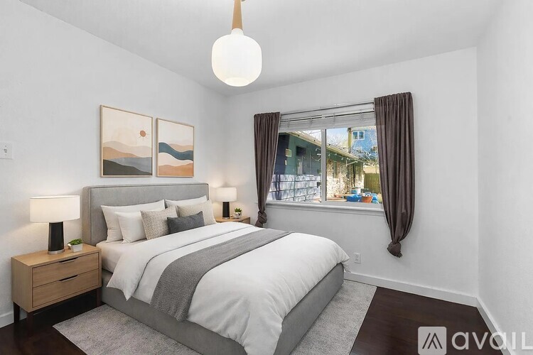 A bedroom with a large bed, a nightstand with a lamp, and a painting on the wall.