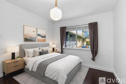 A bedroom with a large bed, a nightstand with a lamp, and a painting on the wall.