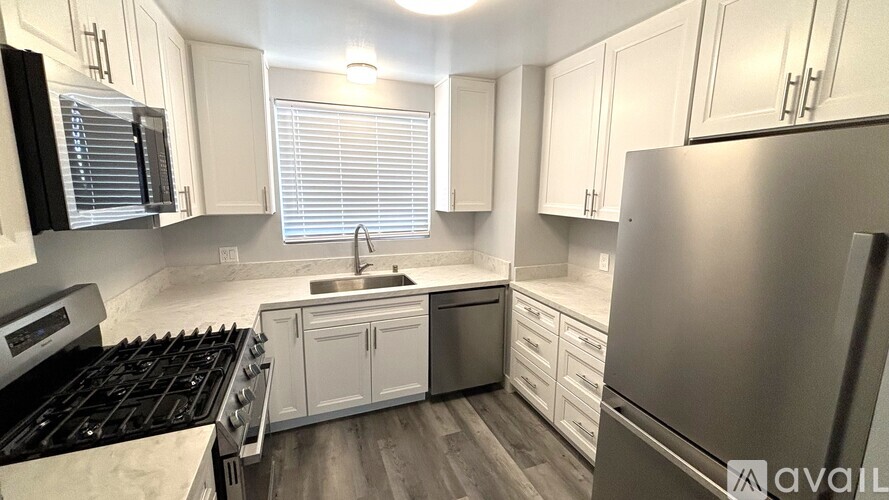 A kitchen with white cabinets and a stainless steel refrigerator.
