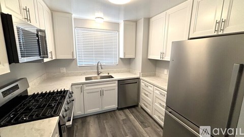 A kitchen with white cabinets and a stainless steel refrigerator.