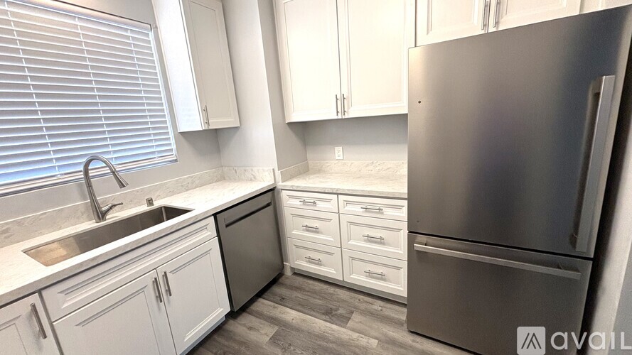 A kitchen with white cabinets and a stainless steel refrigerator.