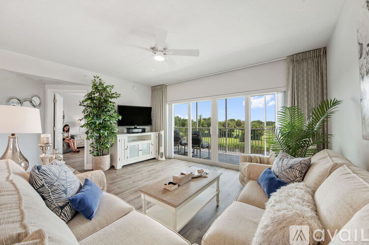 A living room with a couch, a coffee table, a television, and a window with a view of the outdoors.
