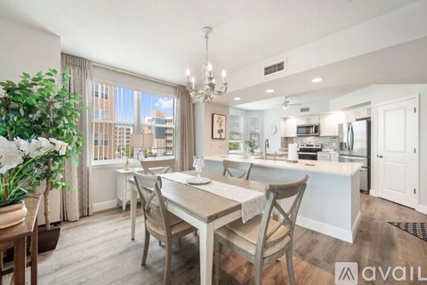 A dining room with a table set for four and a kitchen in the background.