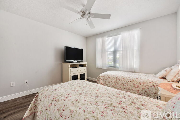 A bedroom with two beds and a television on a dresser.