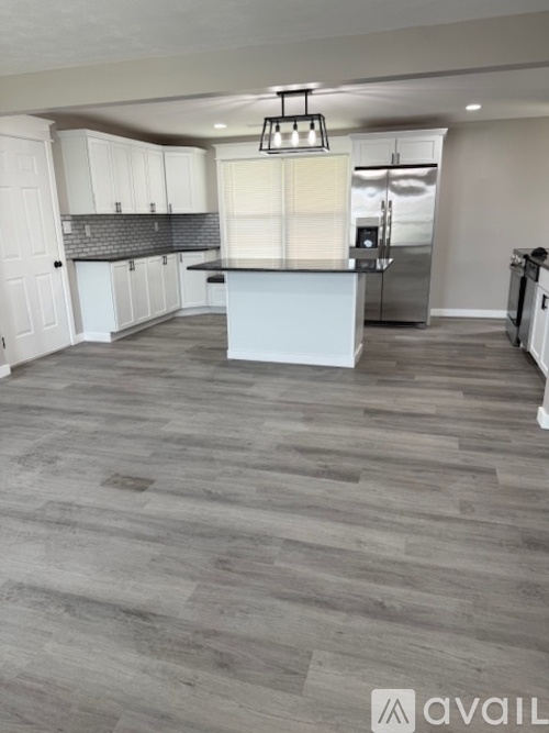 A kitchen with a white island and wooden flooring.