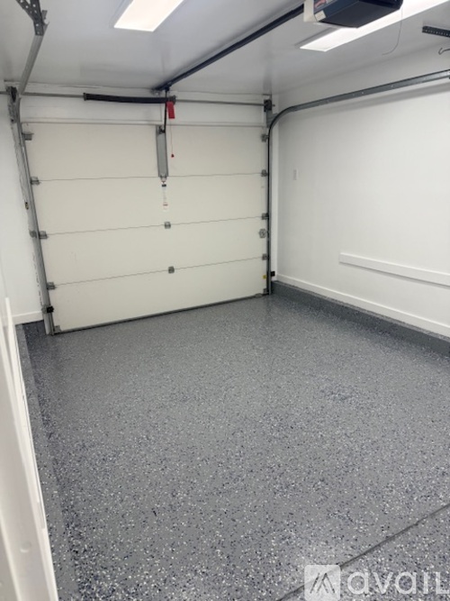 A spacious garage with a white door and grey floor.