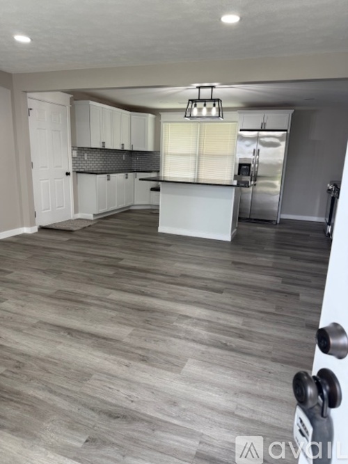 A kitchen with white cabinets and a grey floor.