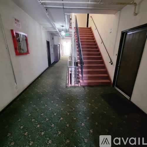 A hallway with a staircase and a fire exit sign on the wall.