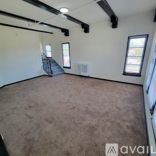 A spacious room with a staircase and a window.