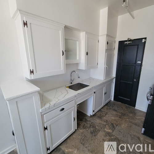 A kitchen with white cabinets and a black door.