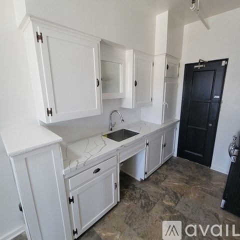 A kitchen with white cabinets and a black door.