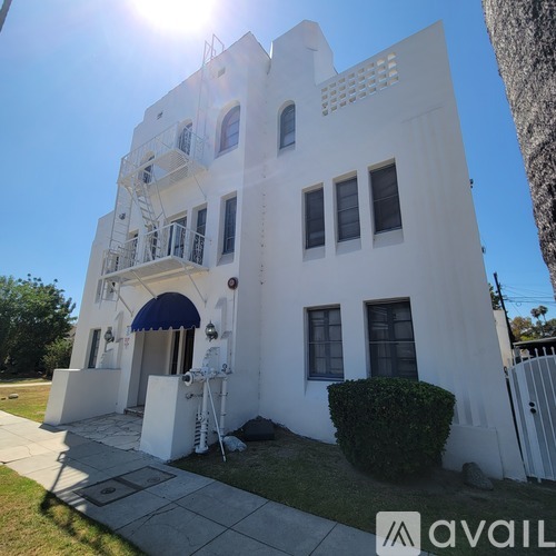A white building with a blue awning and a sign that says "avail" in front of it.