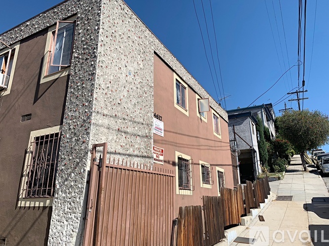 A house with a brown fence and a wall covered in small square tiles.