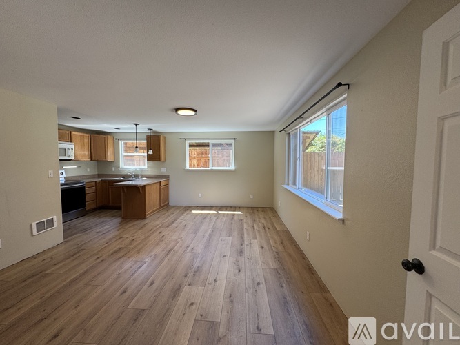 A spacious room with wooden flooring and a large window.