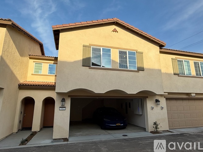 A beige house with a car in the garage.