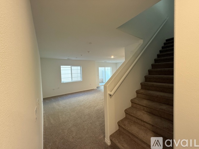 A staircase with a carpeted floor and a window in the background.