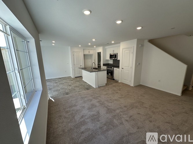 A spacious living room with a kitchen area in the background.