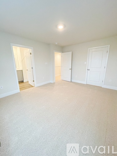 A spacious empty room with white walls and carpeted floor.