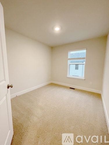 A carpeted room with a door and a window.