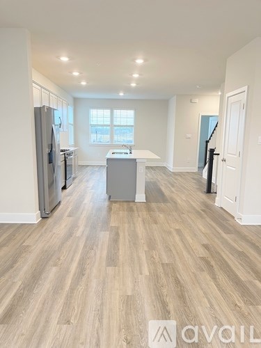 A spacious kitchen with wooden flooring and a refrigerator.