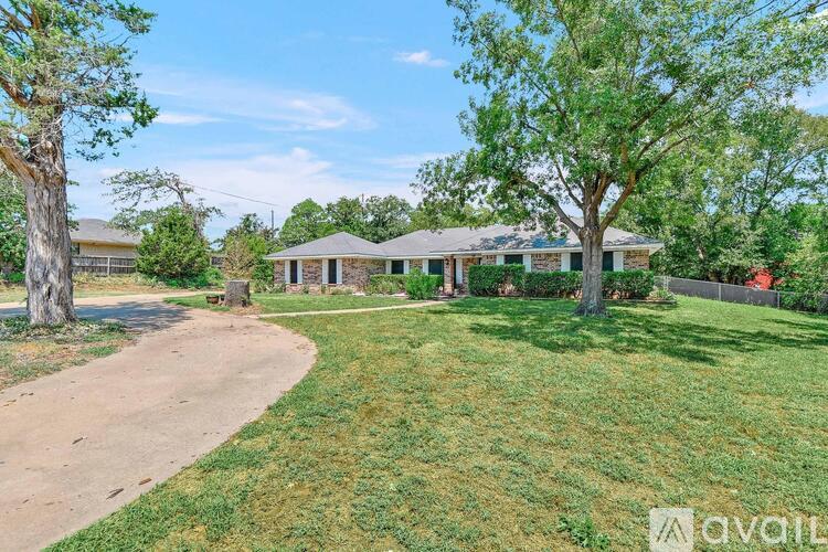 A house with a driveway and trees in front of it.
