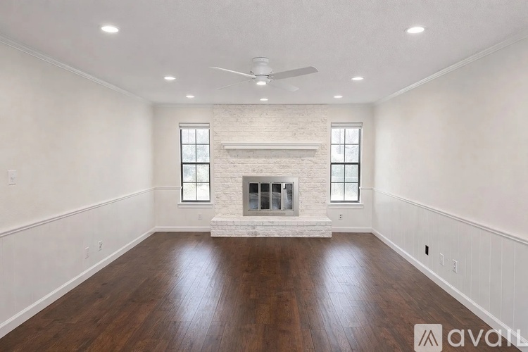 A spacious room with a fireplace and wooden floors.