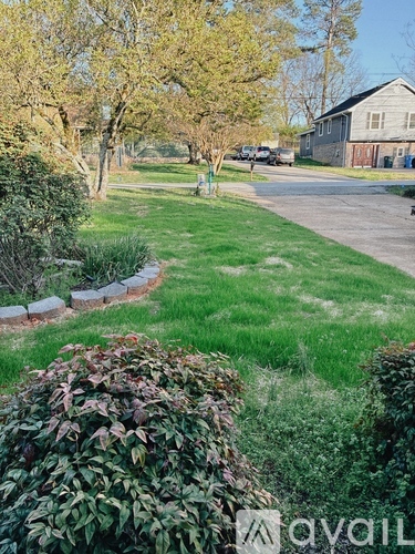 A residential area with a house, trees, and a grassy lawn.