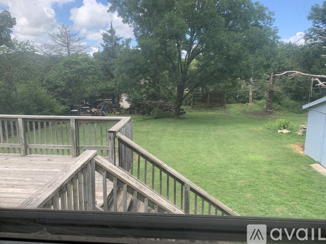 A wooden deck with a railing overlooks a grassy area.