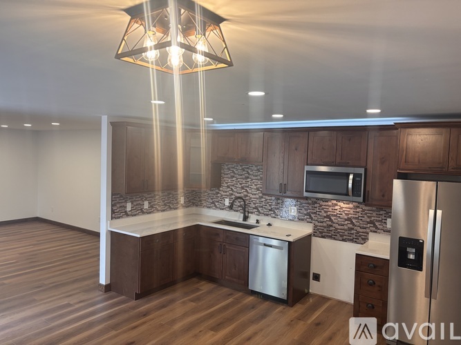 A kitchen with wooden cabinets and a stainless steel refrigerator.